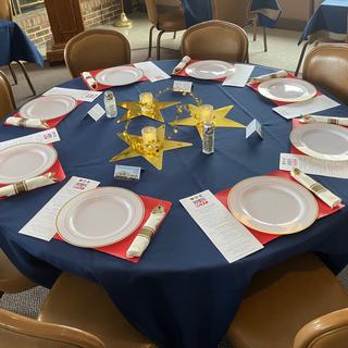 Metallic gold stars on navy blue table linens with LED flicker "flame" candles and votive vases