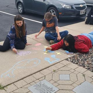 Students using sidewalk chalk at our Chamber of Commerce  for Homecoming Activities!