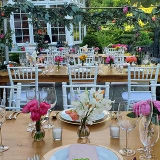 Pink vases lined on farm tables with table garland swag above