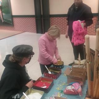 An artist filling her cross necklace with various color sand!