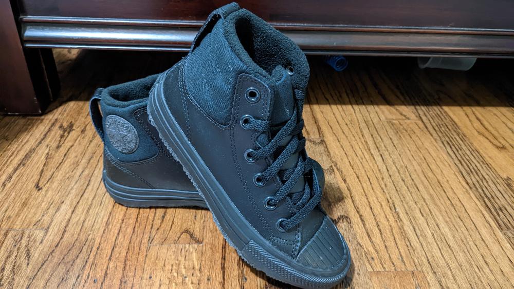 These Converse High Tops are sturdy and well made. They have a nice grippy tread that feels thick enough to wear well, but also flexible enough to play in. The seams are flexible and well sealed, and should hold up well to climbing or light puddle jumping, whatever the day may bring.

The insoles of the shoes are thick and springy, and are comfortable to wear all day long. They have a fleece or felt lining, adding comfort and softness to the inside of the shoe, and helps the ankles feel well supported. 

The design is elegant and versatile. The all black leather plus black laces will make it easy to pair with a variety of outfits, and the grey accents break up any monotony and add interest. 

If I had any complaints about the shoes, it might be that the rubber on the toes feels a bit inflexible, but they might soften up over time when more broken in. As they are it will hold up well against wet weather and keep feet dry and comfortable.